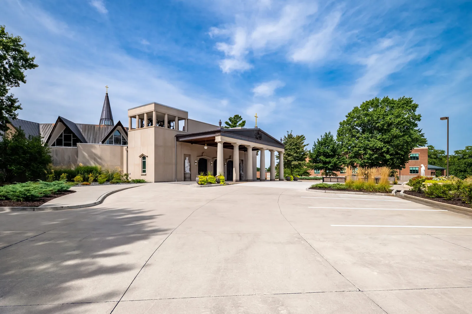 The cathedral across its paved forecourt: the colonnaded portico and stone entrance tower beneath a wide sky.