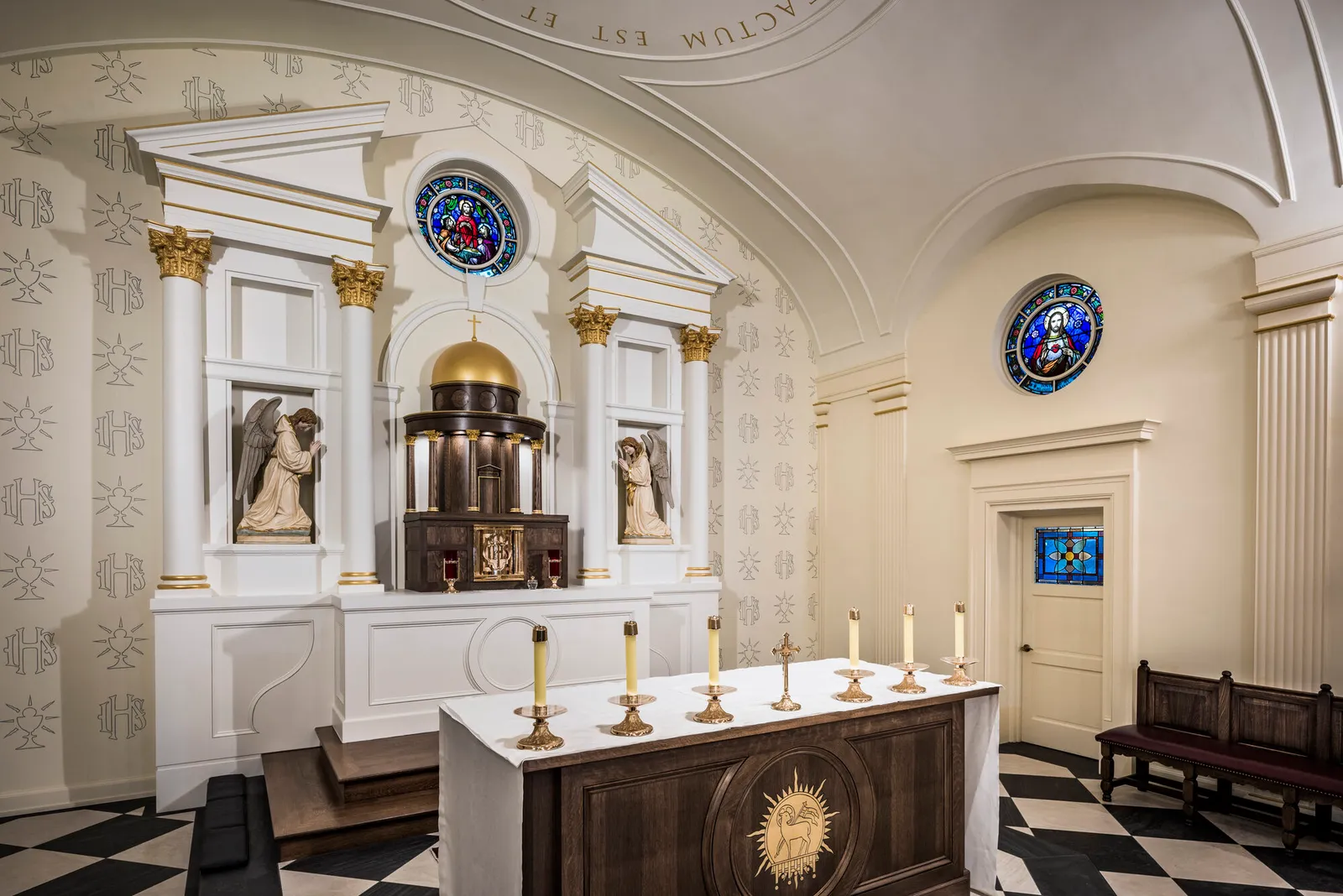 Angled interior view of the sanctuary showing the tabernacle dome, angel statues, and a round stained-glass window of the Sacred Heart.