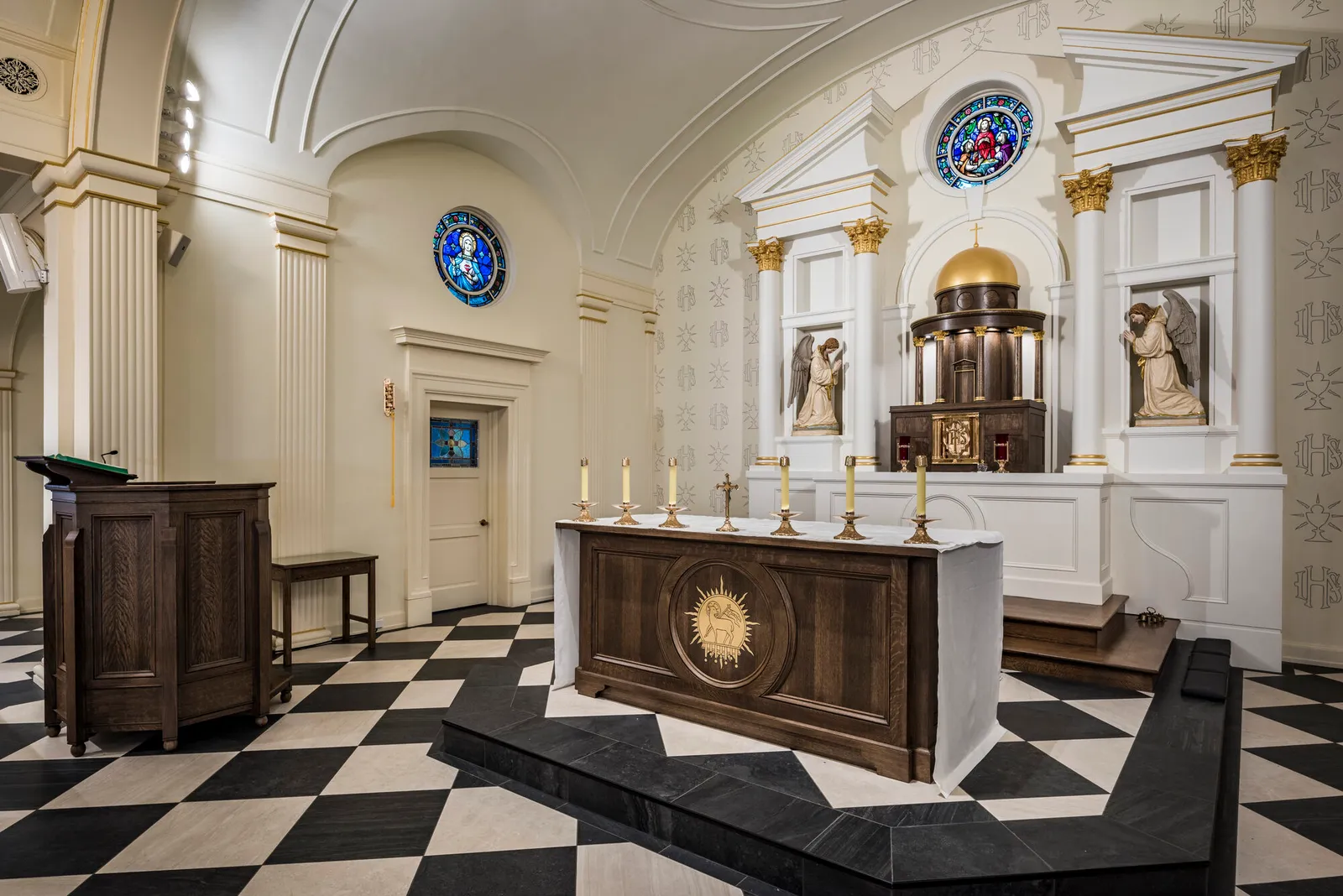 The altar set with candlesticks and a crucifix, with the domed tabernacle and kneeling angel statues behind.