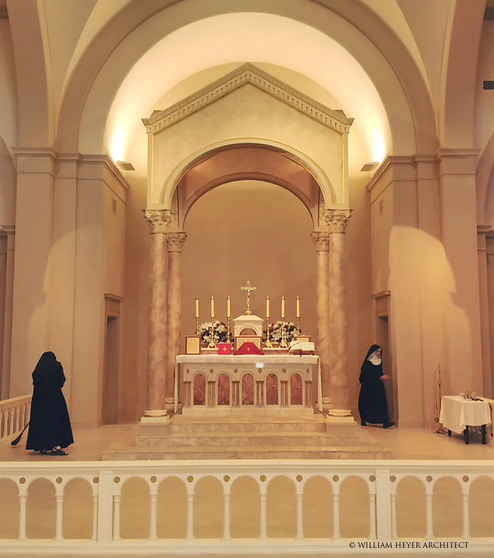 The sanctuary altar under an arched marble canopy, flanked by two nuns, decorated with candles and flowers.