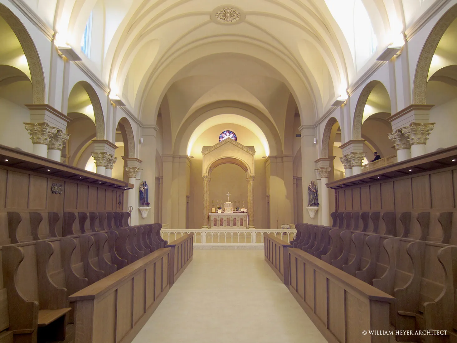 View down the nave of the abbey church toward the sanctuary, flanked by wood choir stalls beneath a vaulted ceiling.