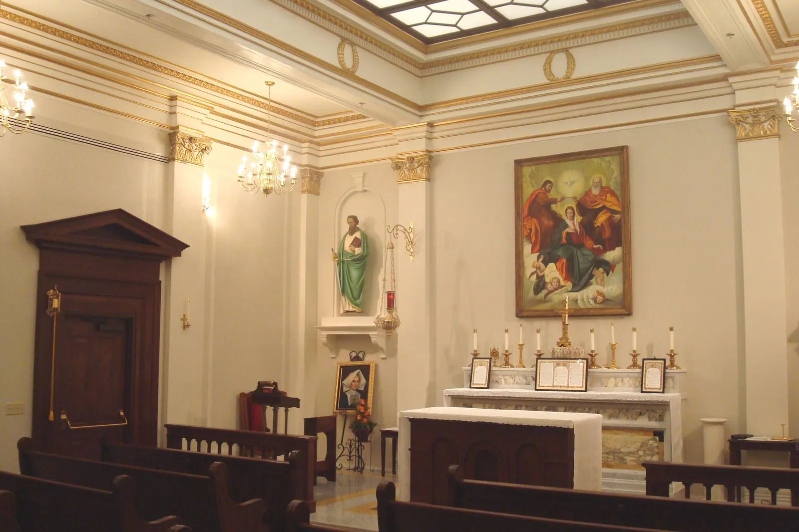 Chapel interior with marble altar, gilded cornice, skylight, and a painting of the Holy Family