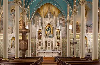 Gothic nave with painted blue ceiling and ornate white high altar seen down the center aisle