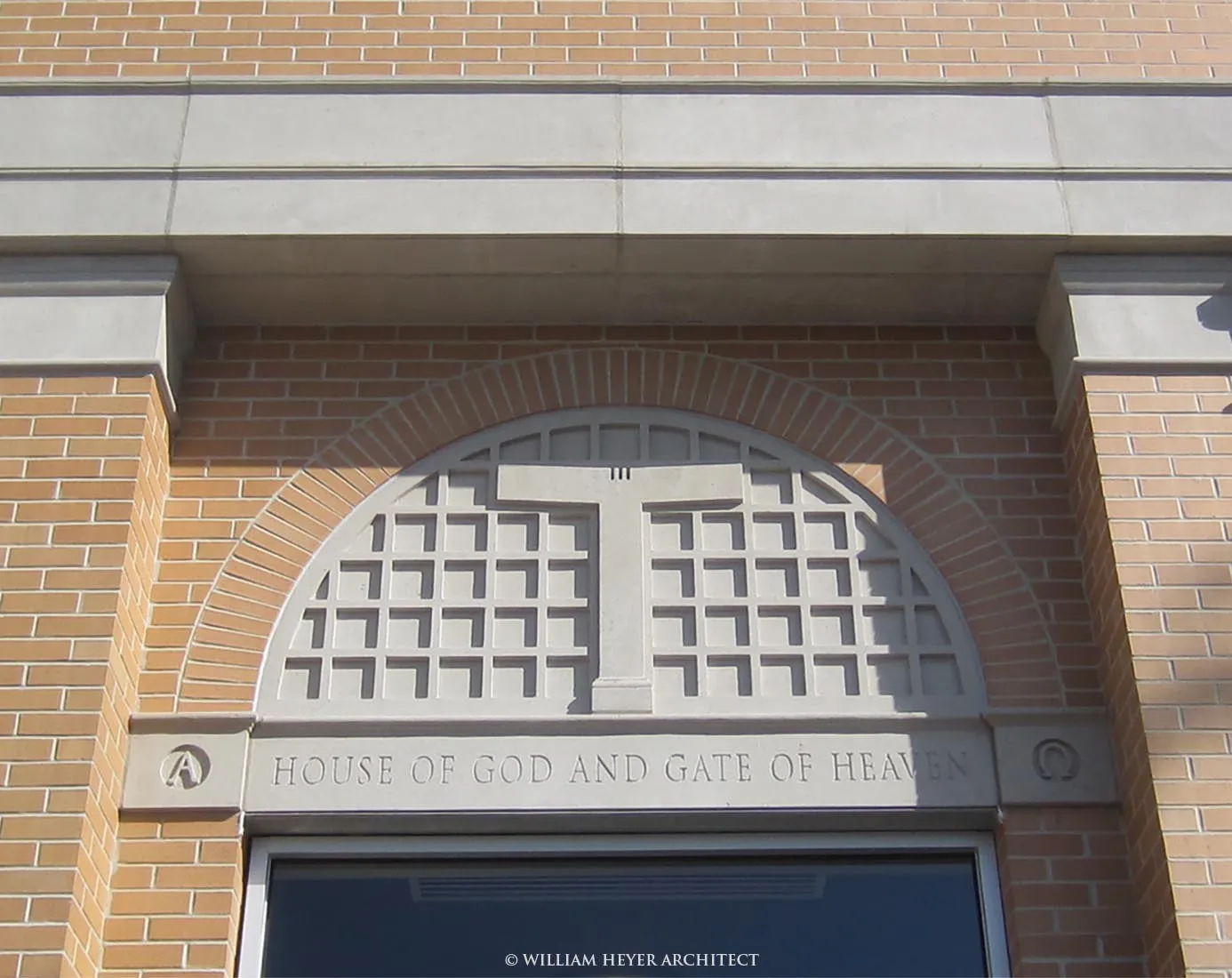 Detail of the entrance: a carved stone inscription over the doors beneath a latticed stone transom, set in the brick front.