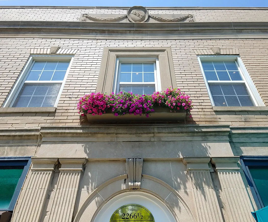 The office of William Heyer Architect on East Main Street, Columbus: a 1927 brick facade with a stone-framed arched entrance and a window box of flowers