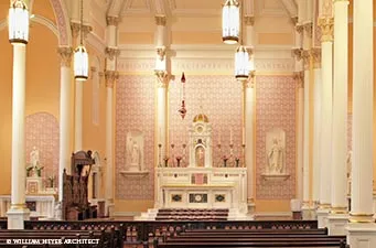 Sanctuary with white marble altar, patterned rose walls, statues in niches, and hanging lamps