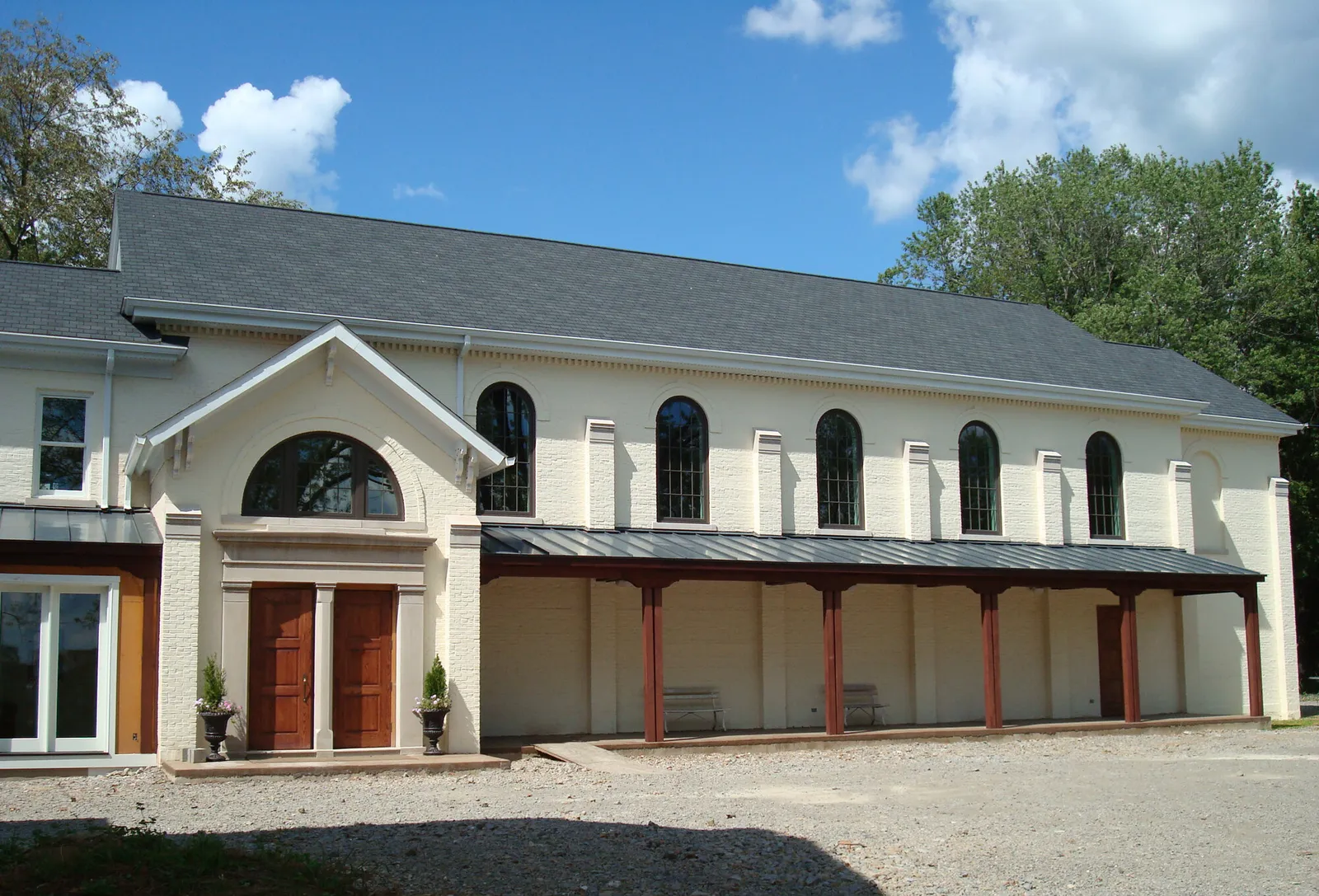 White-painted brick church exterior with arched windows, gabled entry, and covered walkway