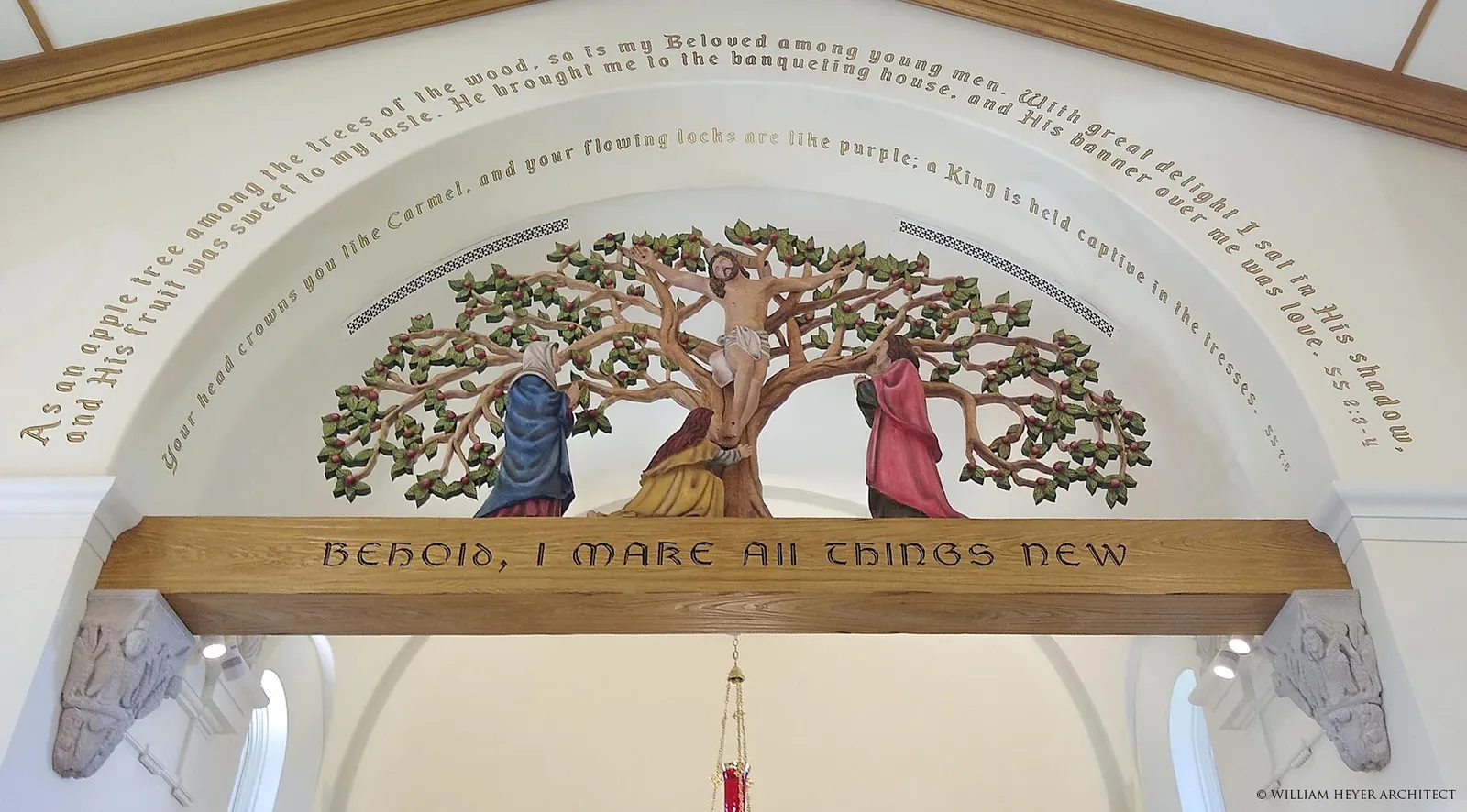 The rood beam and carved tree of life over the sanctuary arch, a painted inscription arching above and lettering along the beam.