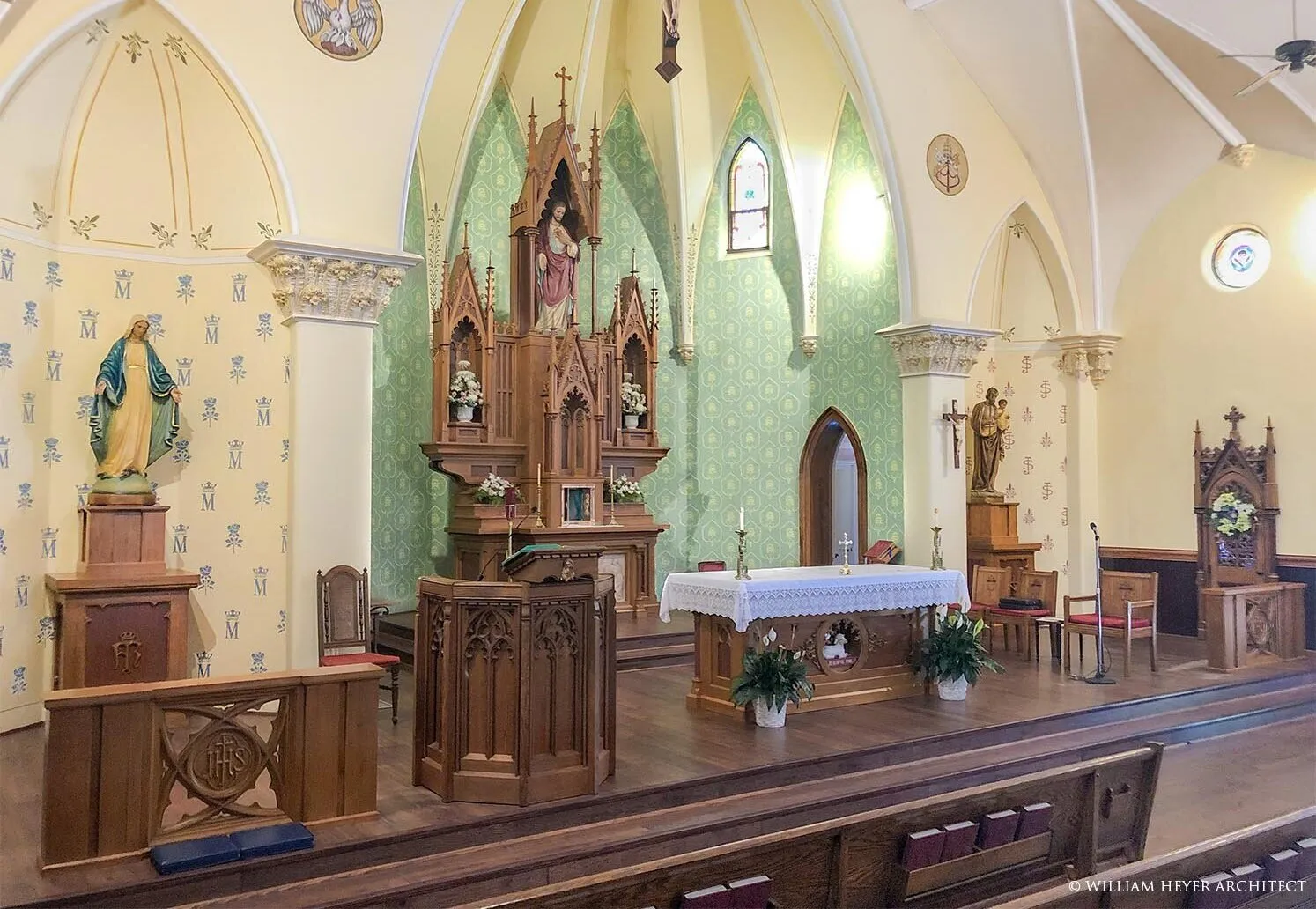 Gothic sanctuary with carved wooden reredos and pulpit against pale green walls