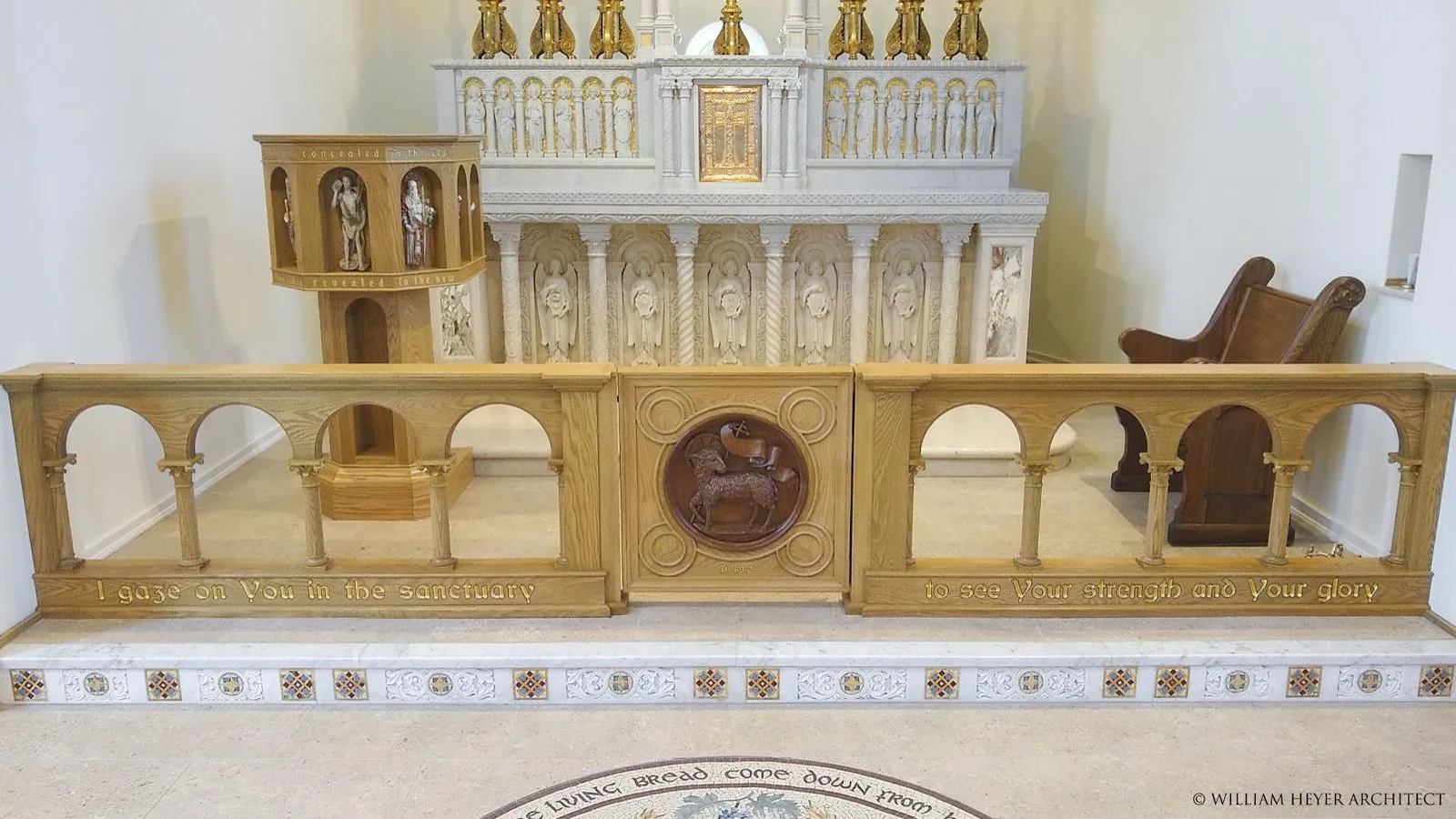 The sanctuary: the white marble reredos and gilded tabernacle behind the oak altar rail, with carved lettering along the rail's base.