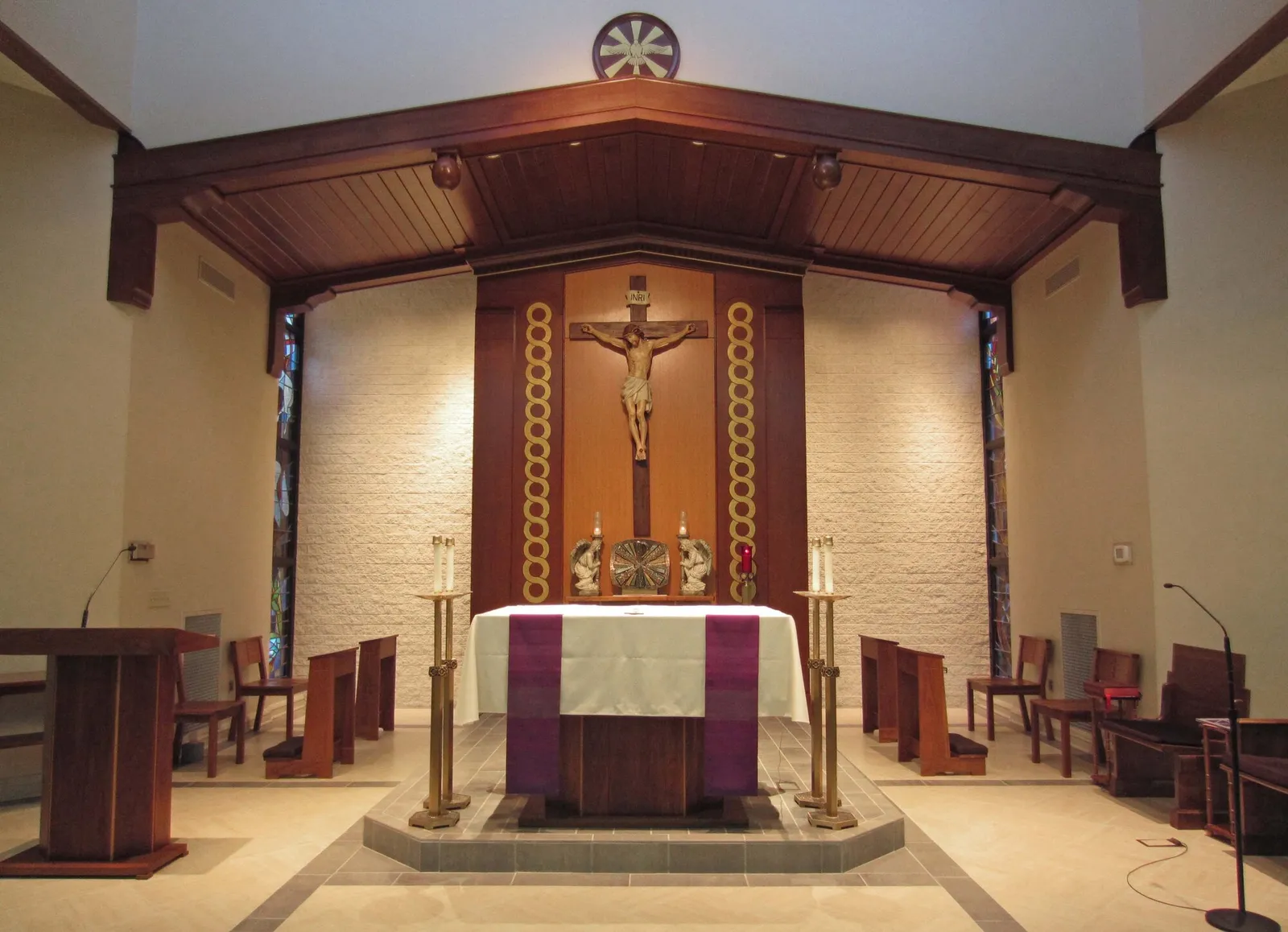 Sanctuary with crucifix on a wood-paneled wall beneath a broad timber canopy