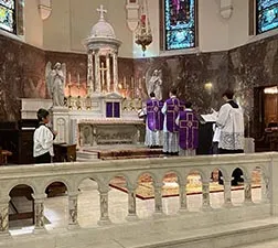 Clergy in purple vestments at a marble high altar behind a carved communion rail