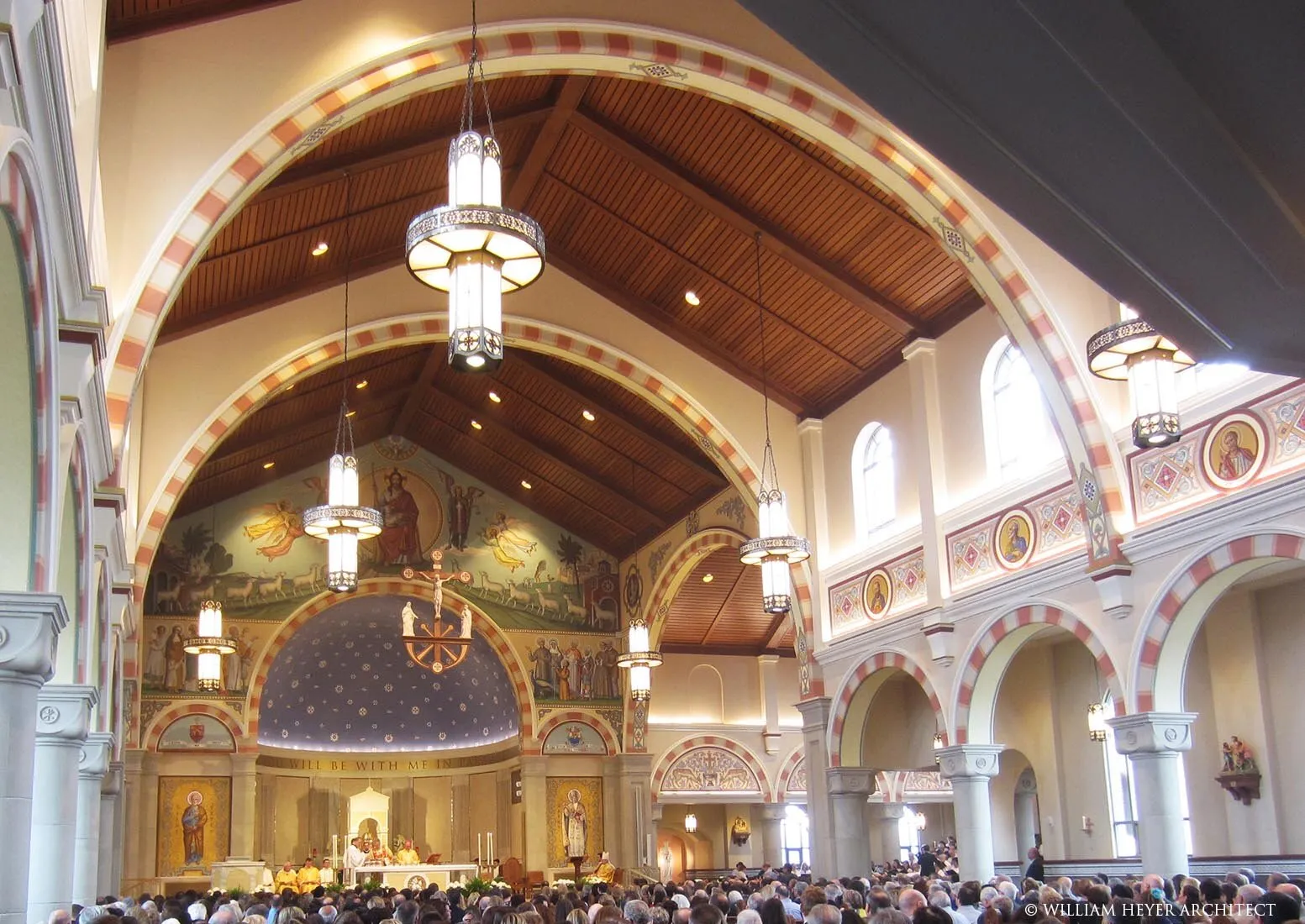 Romanesque nave with banded arches, wood ceiling, murals, and a starred half-dome apse
