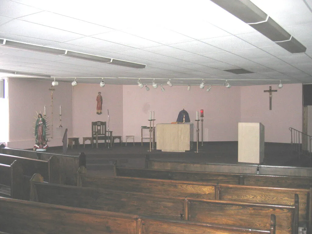 The nave before renovation, with plain wood pews, mauve walls, and a simple sanctuary.