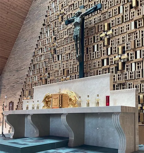 Long marble altar with gilded tabernacle beneath a crucifix on a sculpted block wall